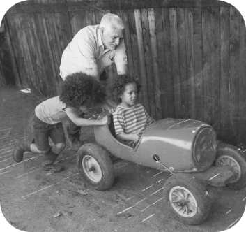 Man pushing a child in a toy car